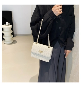 Détail du sac bandoulière tissé crème avec chaîne dorée et fermoir pivotant chic