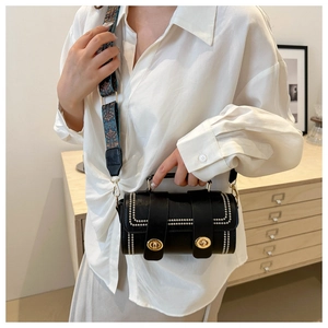 Detail of a black cylinder handbag with silver rivets and bohemian jacquard shoulder strap