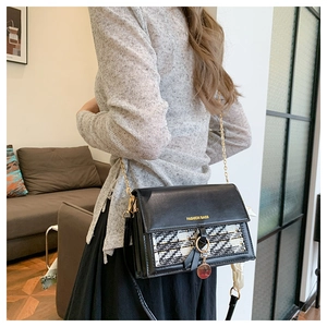 Side view of a trendy tweed and black leather crossbody square bag with gold chain strap