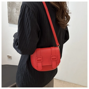 Fashionable red semi-circle saddle bag for women worn over a black pleated top