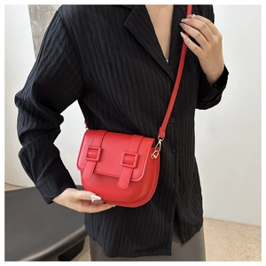 Detailed view of a bright red saddle bag worn by a model with dual buckle accents