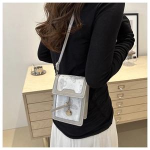 Detail of white printed crossbody phone bag with butterfly pattern and metal charm