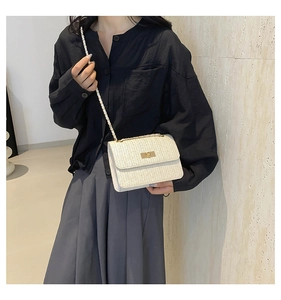 Close-up of cream woven crossbody bag with gold lock and chain strap on model