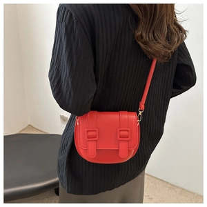 Side view of red PU leather saddle bag with double buckle straps on female model