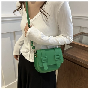 Detailed view of a bright green saddle bag featuring double decorative straps and gold buckle