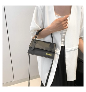 Sac bandoulière noir porté par un mannequin avec détails dorés et rabat élégant