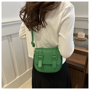 Close-up of grass green saddle bag with dual buckles and adjustable shoulder strap