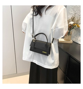 Détails d'un sac bandoulière noir minimaliste avec finitions dorées et logo