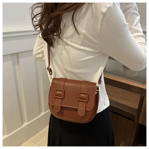 Detailed side view of a brown vintage saddle bag with decorative straps and golden hardware