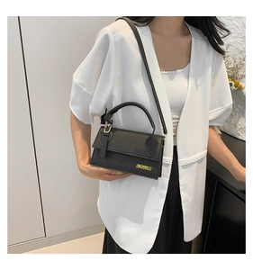 Détail d'un petit sac bandoulière noir minimaliste avec logo doré et bandoulière