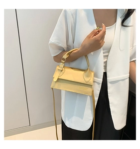 Détail du sac bandoulière jaune avec boucle en métal et logo sur cuir synthétique texturé
