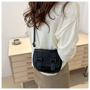 Detailed back view of a minimalist black leather saddle bag with double buckle accents