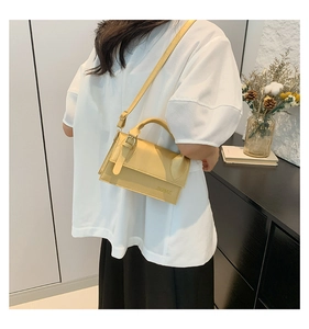 Détail d'un sac à bandoulière en cuir jaune avec boucle en métal et logo embossé chic