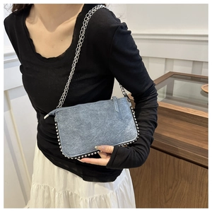 Détail du sac en jean bleu avec garniture perlée argentée et bandoulière métallique