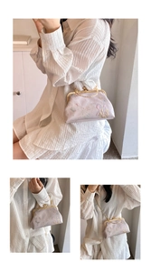 Macro view of light purple satin bag featuring floral embroidery and gold metal clasp