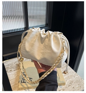 Dettaglio della borsa a secchiello plissettata bianca con catena dorata e coulisse