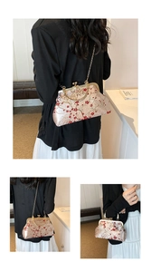 Detailed view of floral embroidery on cream satin handbag with pearl and metal handles