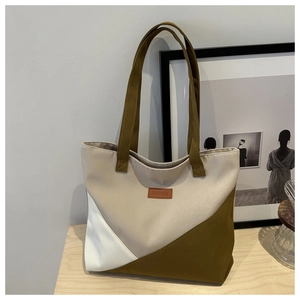 Detail of color-block canvas tote bag with brown leather FASHION label on wooden table