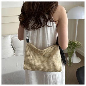 Detail of woven straw tote bag with silver chain and black leather wide shoulder strap