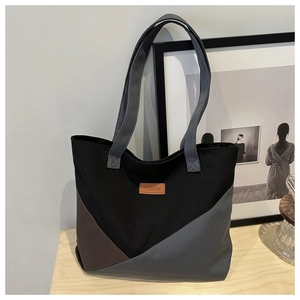 Detailed close-up of color-block canvas tote bag on a wooden table with fashion tag