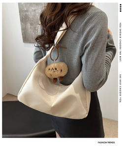 Detail of soft cream hobo bag with plush brown doll charm and adjustable wide strap
