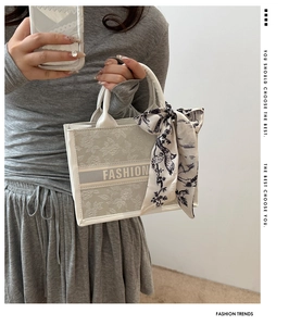 Detail of embroidered beige tote bag featuring floral patterns and a decorative silk scarf