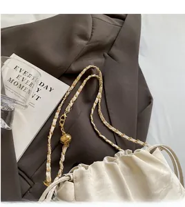Dettaglio della borsa a nuvola bianca con catena dorata sopra un blazer marrone