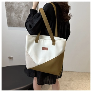 Detail view of a large canvas tote bag with olive green and beige color-block design
