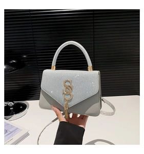 Detail of light grey crossbody bag with silver crystal flap and golden SS hardware
