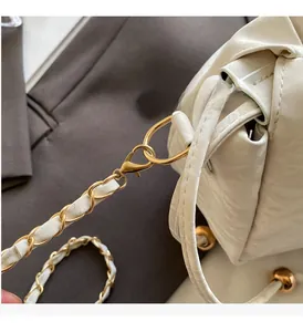 Dettaglio della catena in metallo dorato e della trama in ecopelle crema della borsa