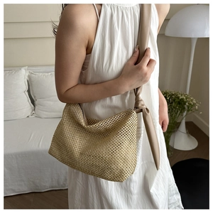 Detail of woven straw tote bag with knotted faux leather shoulder strap for summer vacation