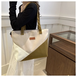 Detail of color-block canvas tote bag with leather FASHION label on model shoulder