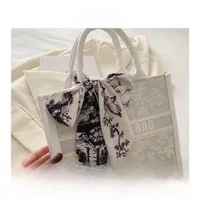 Detail of floral embroidered tote bag featuring branded webbing and decorative silk scarf