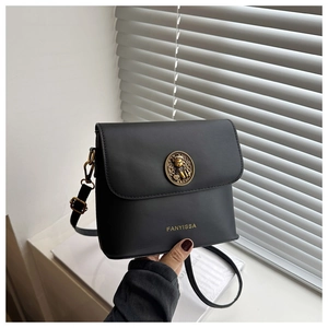 Detail of vintage gold emblem and embossed logo on black PU leather crossbody bag