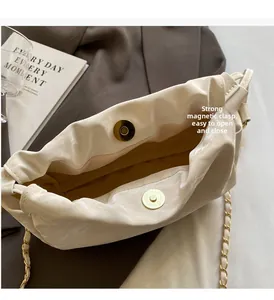 Dettaglio borsa a secchiello off-white con doppia chiusura magnetica e catena dorata