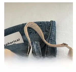 Detail view of light blue denim tote bag with canvas shoulder strap and metal buckle adjustment