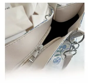 Detail of smooth silver zipper and floral faux leather texture on the tote bag