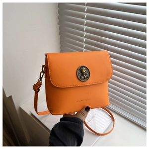 Close-up of vibrant orange crossbody bag featuring a vintage gold bear emblem buckle