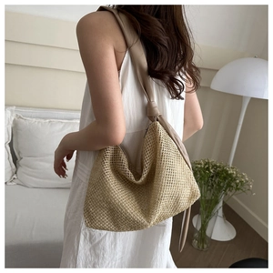 Detail of the woven texture and wide beige strap on this bohemian straw tote bag