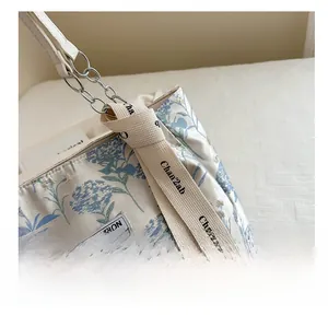 Detail of floral tote bag featuring silver chain strap and creative ribbon decoration