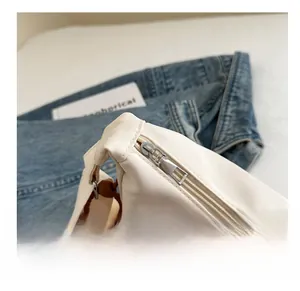 Close-up of smooth metal zipper and waterproof nylon fabric on cream white shoulder bag