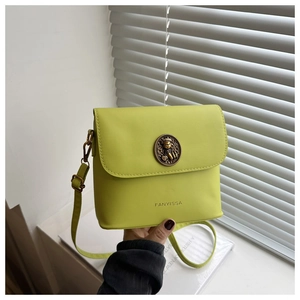 Detail of lime green crossbody bag featuring a bronze animal emblem and embossed brand logo