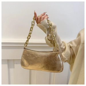 Detail of gold chain strap and textured metallic surface on the shoulder baguette bag
