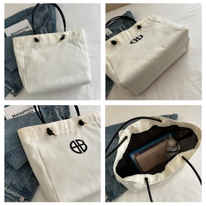 Detailed view of white nylon tote bag showing brand logo, spacious interior, and black handles
