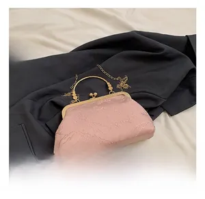 Detail of pink jacquard fabric evening bag with vintage metal clasp and gold chain strap