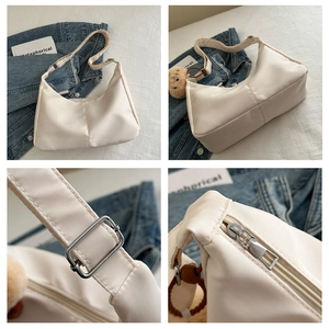 Close-up details of cream nylon shoulder bag featuring adjustable silver buckle and zipper