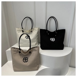 Detailed view of canvas tote bags in black, white, and beige with geometric logos