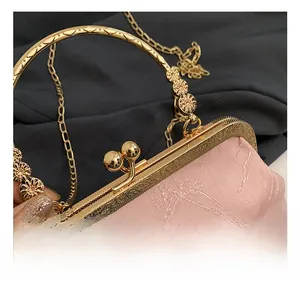 Macro detail of pink floral embroidery fabric and vintage golden metal clasp on handbag