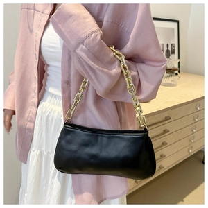 Detail of a black synthetic leather underarm bag with a bold gold chain strap