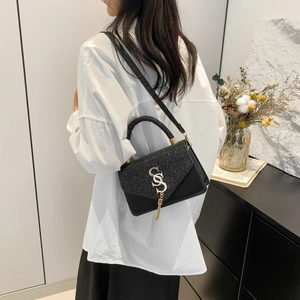 Elegant black leather handbag with glitter flap, golden fringe, and stylish S logo